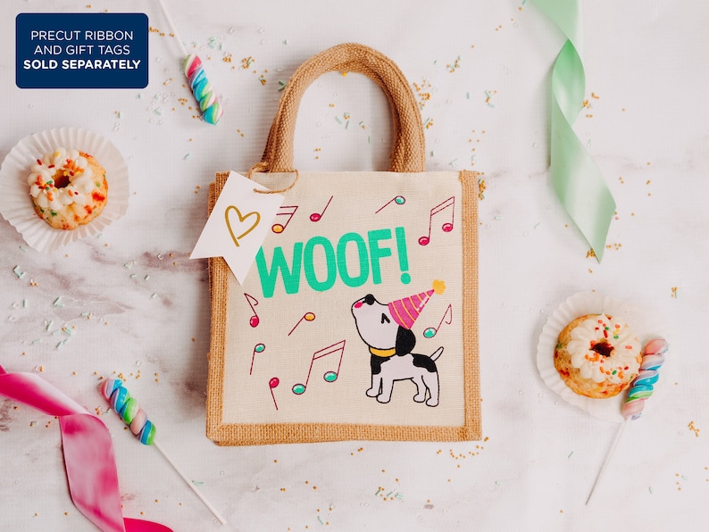 May include: A small brown hessian tote bag with a white handle. The bag features a cartoon dog wearing a party hat and the words "Woof!" in green lettering. The bag is surrounded by confetti and other party decorations.