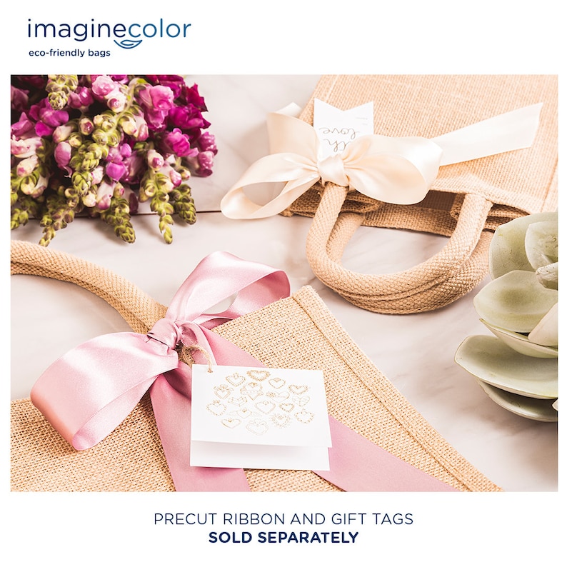 May include: Two burlap gift bags with pink and cream ribbon bows. One bag has a white gift tag with gold hearts. The text "Precut ribbon and gift tags sold separately" is at the bottom of the image.