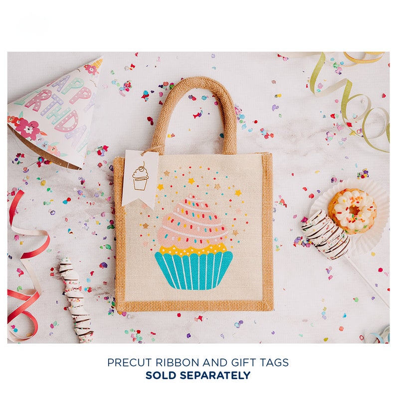 May include: A small, beige hessian tote bag with a colourful cupcake design. The bag has a brown handle and a white tag with a cupcake illustration. The bag is surrounded by confetti and other party decorations.