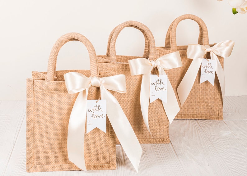 May include: Three brown burlap tote bags with white satin ribbon bows and white tags that say "with love".