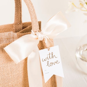 May include: A burlap tote bag with a white satin ribbon and a gift tag that says "with love".
