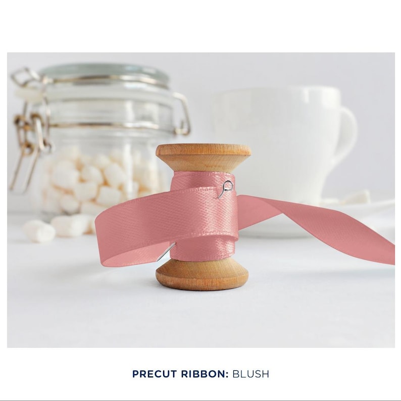 May include: A spool of blush pink ribbon with a wooden base. The ribbon is wrapped around the spool and is ready to be used for crafting or decorating.
