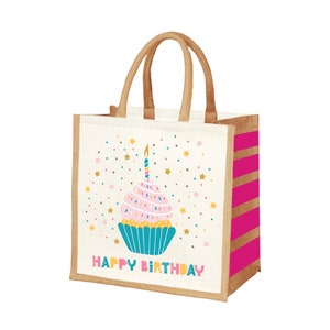 May include: A white jute tote bag with pink and gold stripes. The bag features a colorful cupcake with a lit candle and the text "Happy Birthday".