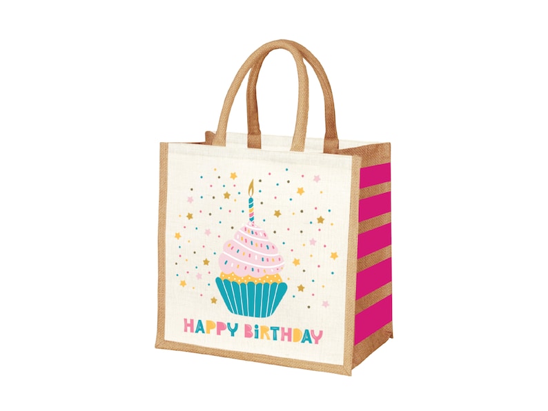 May include: A white jute tote bag with pink and gold stripes. The bag features a colorful cupcake with a lit candle and the text "Happy Birthday".