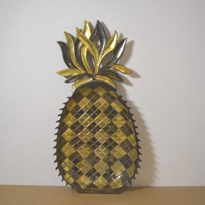 Op de afbeelding: Een decoratieve ananassculptuur met een mozaïekontwerp. De body is een mix van gouden en zwarte vierkanten, met een stekelige omtrek. De bovenkant heeft gouden en zwarte bladeren. De sculptuur is ongeveer 30 cm hoog.
