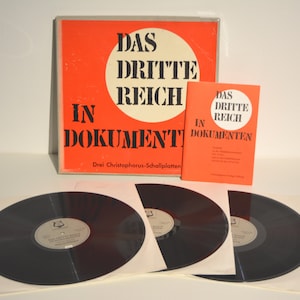 Puede incluir: Un conjunto de tres discos de vinilo negros con etiquetas blancas. Los discos están en una caja de cartón roja y blanca con el texto "Das Dritte Reich in Dokumenten" y "Drei Christophorus-Schallplatten".