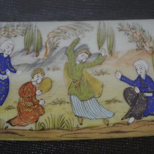 May include: Rectangular, hand-painted miniature scene depicting four figures in traditional attire. The figures are set against a backdrop of trees and a light-colored sky. The figures are in shades of blue, green, and red.