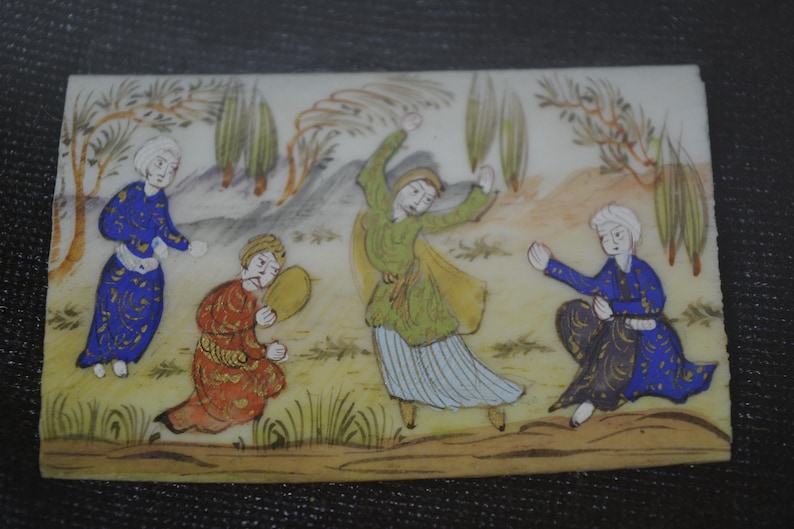 May include: Rectangular, hand-painted miniature scene depicting four figures in traditional attire. The figures are set against a backdrop of trees and a light-colored sky. The figures are in shades of blue, green, and red.
