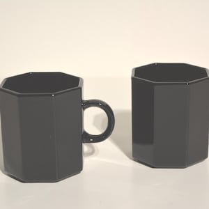 Peut inclure: Deux tasses octogonales noires avec des anses. Les tasses sont en verre et ont une finition lisse et brillante.