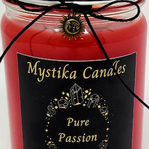 May include: A red candle in a glass jar with a black lid. The label reads "Mystika Candles" and "Pure Passion." A black string is tied around the jar, adorned with a sun charm. The candle is 12 oz.
