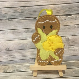 Embroided gingerbread man holding March's flower the daffodil