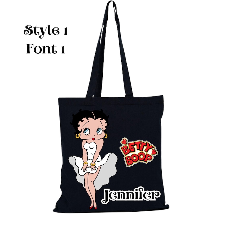 May include: Black tote bag with a white cartoon image of Betty Boop wearing a white dress. The bag has the text "Betty Boop" and "Jennifer" printed on it.