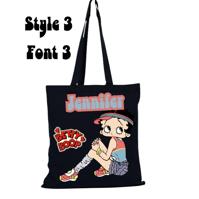 May include: Black canvas tote bag with a cartoon image of Betty Boop wearing a red and white baseball cap and a blue and white striped shirt. The bag has the name "Jennifer" printed in a retro font.