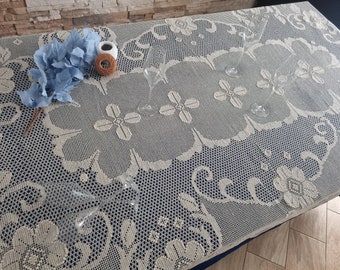 May include: A white crocheted tablecloth with a floral pattern. There are several clear glass wine glasses on the tablecloth.