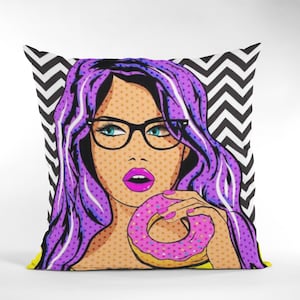 May include: A colorful pop art style pillow featuring a woman with purple hair, wearing glasses and biting into a pink donut with sprinkles. The background is a black and white chevron pattern.