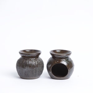 May include: Two brown ceramic oil diffusers with a textured surface. One diffuser has a round opening on the side.