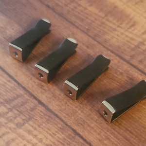 May include: Four black car air fresheners with silver accents. The fresheners are shaped like a rectangle with rounded edges.