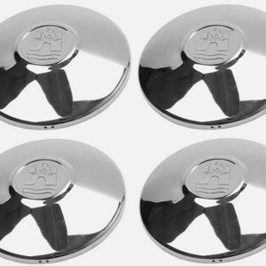 Pode incluir: Quatro calotas cromadas brilhantes. Cada calota tem um centro oval em relevo com um emblema detalhado. As calotas são reflexivas, mostrando reflexos distorcidos. O design é simétrico.