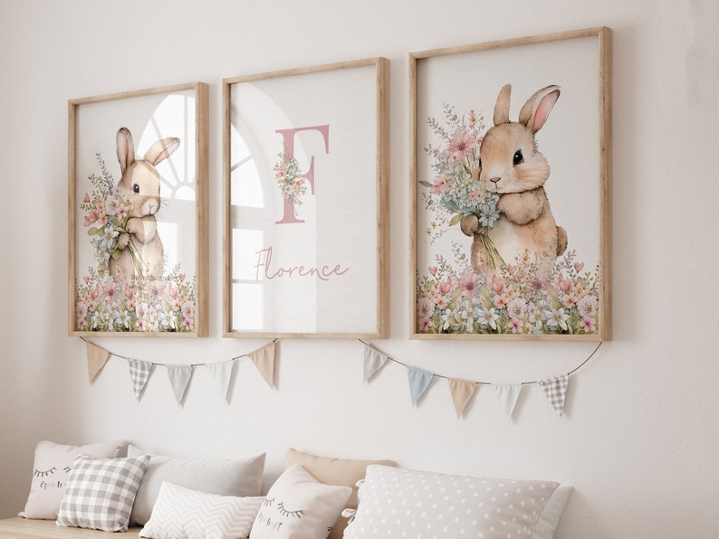 May include: Three framed prints featuring a watercolour illustration of a bunny holding a bunch of flowers. The middle print has the letter "F" and the name "Florence" in pink lettering.