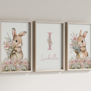 May include: Three framed prints featuring a watercolour illustration of a bunny holding flowers. The centre print has the letter "I" with flowers and the name "Isabella" beneath it.