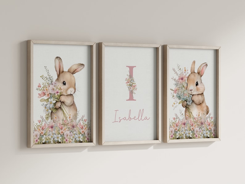 May include: Three framed prints featuring a watercolour illustration of a bunny holding flowers. The centre print has the letter "I" with flowers and the name "Isabella" beneath it.