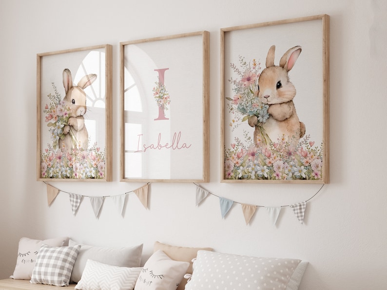May include: Three framed prints featuring a watercolour illustration of a bunny holding a bunch of flowers. The middle print has the name "Isabella" written in pink lettering.