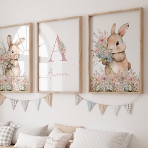 May include: Three framed prints featuring a watercolour illustration of a bunny holding flowers. The middle print has the letter A and the name Aurora written in pink.