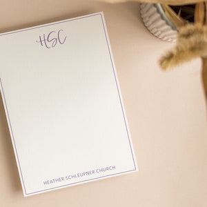 May include: A white notepad with a purple border and the text "HSC" and "HEATHER SCHLEUPNER CHURCH" printed on it.