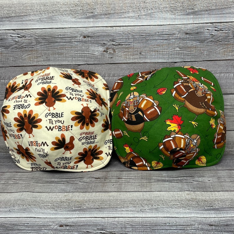 May include: Two fabric bowl covers, one with a green background and a pattern of turkeys wearing football uniforms and the other with a beige background and a pattern of turkeys with the text "Gobble 'til you wobble!" repeated.