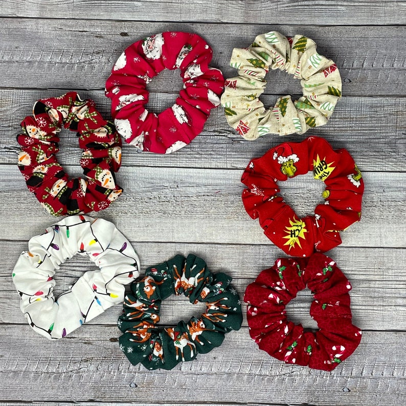 K&ouml;nnte beinhalten: Satz von zehn Weihnachts-Scrunchies in verschiedenen Farben und Mustern, darunter Rot, Gr&uuml;n, Wei&szlig; und Braun. Die Scrunchies zeigen Weihnachtsmotive wie Schneem&auml;nner, Lichter und Rentiere.