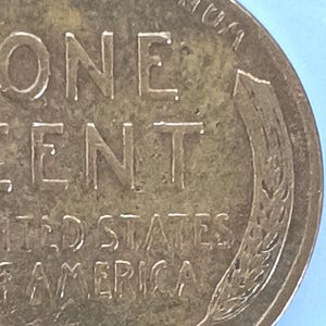 Op de afbeelding: Close-up van een koperkleurige Amerikaanse penny met de woorden "ONE CENT" en "UNITED STATES OF AMERICA" gegraveerd op de voorkant.