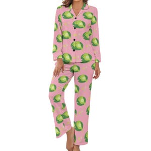 May include: Pink pajamas with a green frog print. The pajamas have long sleeves and long pants.