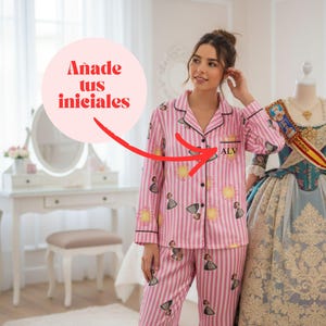 May include: Pink striped pajama set with a sun and figure pattern. The pajama top has black trim and the initials "ALV" embroidered on the chest. The text "Añade tus iniciales" is in a pink circle.