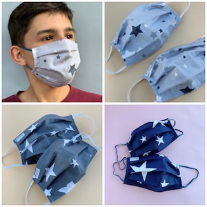Puede incluir: Cuatro mascarillas reutilizables con un patrón de estrellas. Dos mascarillas son azules con estrellas blancas, y dos mascarillas son grises con estrellas blancas y negras.