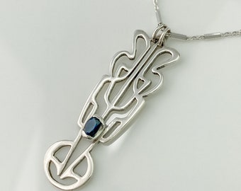Op de afbeelding: Een zilveren hangerketting met een Art Nouveau-ontwerp. De hanger heeft een langwerpige vorm met ingewikkelde uitgesneden patronen en een donkerblauwe ovale edelsteen. De ketting heeft een delicate zilveren kleur.