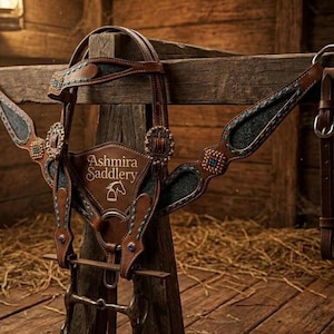 May include: A brown leather horse bridle and breast collar set featuring dark grey textured inlays, turquoise stitching, and decorative metal conchos. The centre chest piece displays the text Ashmira Saddlery with a horse head line drawing icon.