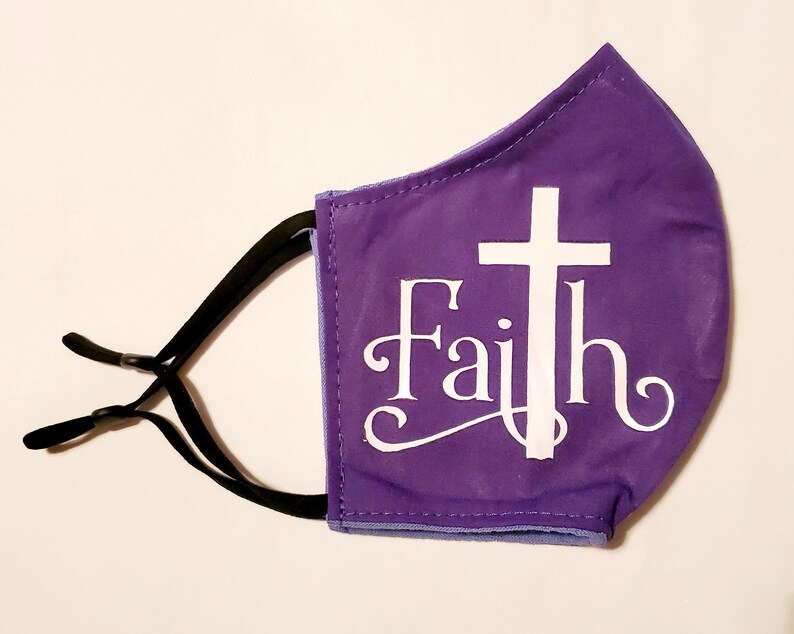 May include: Purple face mask with a white cross and the word "Faith" in a decorative font.