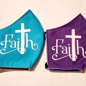 May include: Two face masks with the word "Faith" and a white cross printed on them. One mask is teal blue and the other is purple.