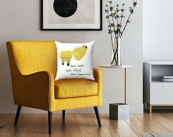 Puede incluir: Un sillón amarillo con un cojín blanco con dos abejas de dibujos animados y el texto "Bee safe, bee kind, bee inspired".