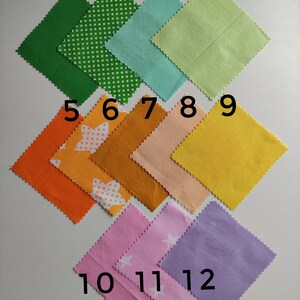 May include: Twelve fabric squares in various colors and patterns, numbered 1 through 12. The squares are arranged in three rows, with four squares in each row. The squares are all the same size and have a scalloped edge.
