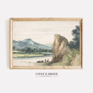 May include: A watercolor painting of a landscape with a river, a cliff, and trees. The painting is framed in a light wood frame. The text "LINEN & GRACE PRINT SHOPPE" is printed below the image.