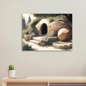 May include: A canvas print showing a stone tomb entrance with a large round stone. The scene is set in a natural landscape with steps leading to the dark opening, surrounded by greenery and flowers. The artwork has a soft, painterly style.