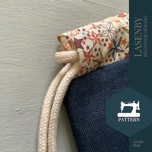 May include: A close-up of a drawstring bag with a navy blue canvas base and a colorful star print lining. The bag has a white drawstring and the text "LASENBY BEGINNER SEWING" is printed on the right side of the image. The text "PATTERN" is printed below a sewing machine icon. The text "LP029 Phili" is printed in the bottom right corner.