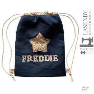 May include: A navy blue drawstring bag with a star-shaped patch and the name "FREDDIE" embroidered on the front. The bag has white drawstrings and a white background on the star patch.