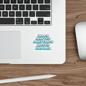 May include: A die-cut sticker featuring the Spanish words for the days of the week: lunes, martes, miércoles, jueves, and viernes. The text is written in a bold, white, sans-serif font with a distinct blue drop shadow, creating a layered effect.