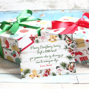 May include: Two wrapped Christmas gifts with colorful patterned paper and green and red ribbons. A greeting card with a Christmas message and decorative elements is in front of the gifts.