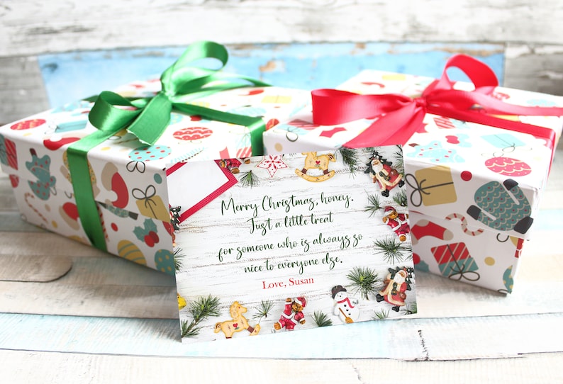 May include: Two wrapped Christmas gifts with colorful patterned paper and green and red ribbons. A greeting card with a Christmas message and decorative elements is in front of the gifts.