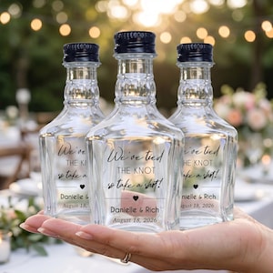 May include: Three clear glass miniature bottles with black screw caps, each featuring a label that reads "We've tied THE KNOT so take a shot!" followed by "Danielle & Rich" and the date "August 18, 2026" with a small heart icon.