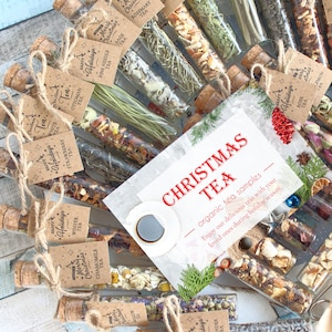 May include: A collection of tea samples in glass tubes with cork stoppers, arranged in a circular pattern. Each tube is labeled with a different tea type. A card in the center reads "Christmas Tea" with a cup of coffee and holiday decorations.
