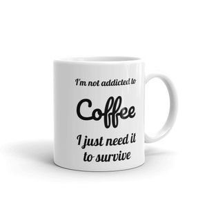 Puede incluir: Taza de café de cerámica blanca con asa curvada. La taza presenta el texto "I'm not addicted to Coffee I just need it to survive" en negro, con una fuente estilizada. La taza está sobre un fondo blanco liso.
